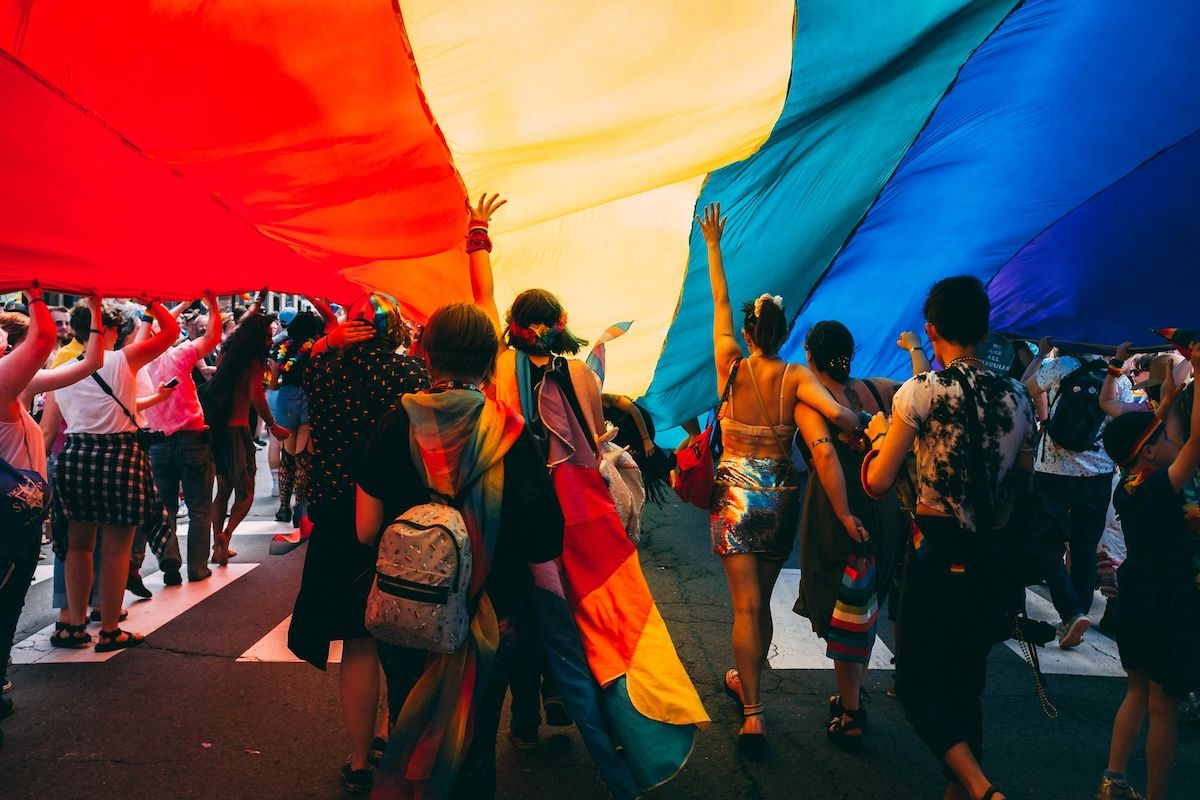 Group of people marching together under a large garment at Pride.
